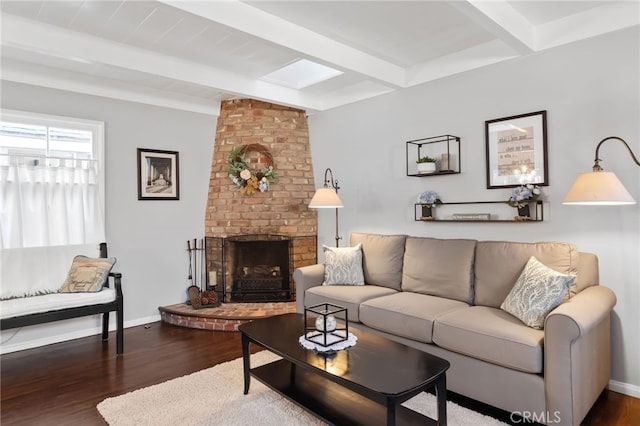 living area featuring a brick fireplace, baseboards, beam ceiling, and wood finished floors