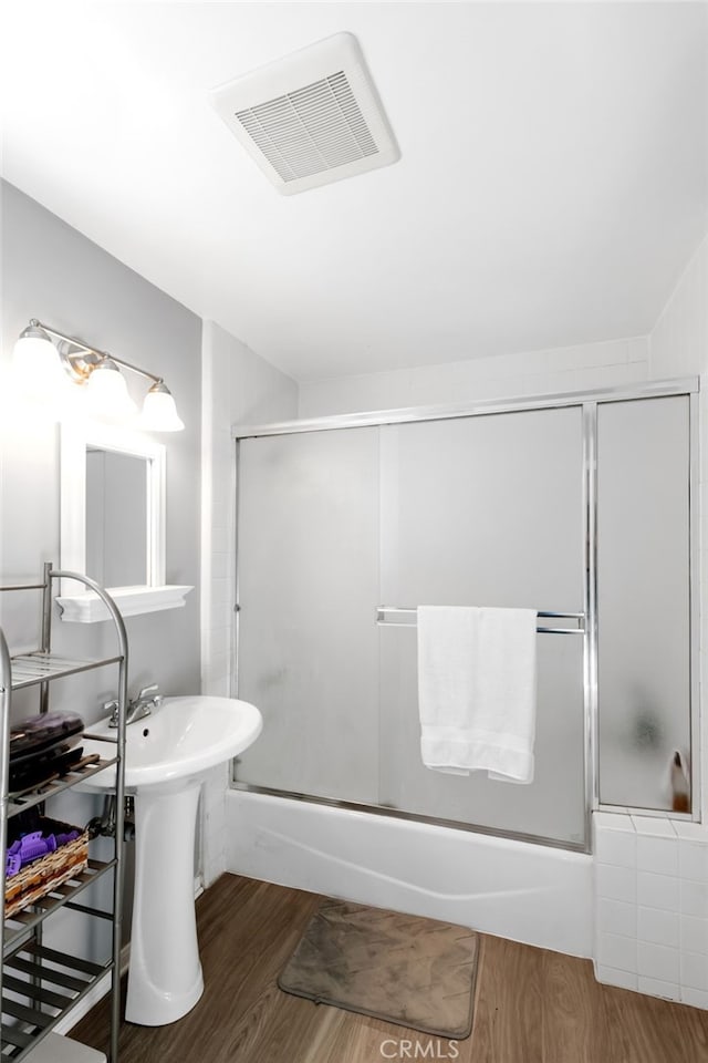 bathroom featuring visible vents, shower / bath combination with glass door, and wood finished floors