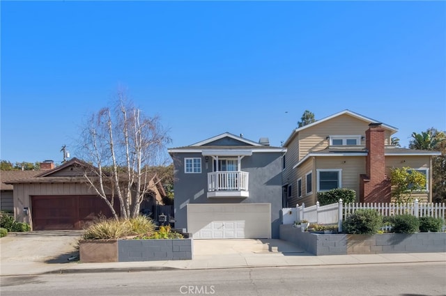 view of front of home with an attached garage, a balcony, fence, concrete driveway, and stucco siding