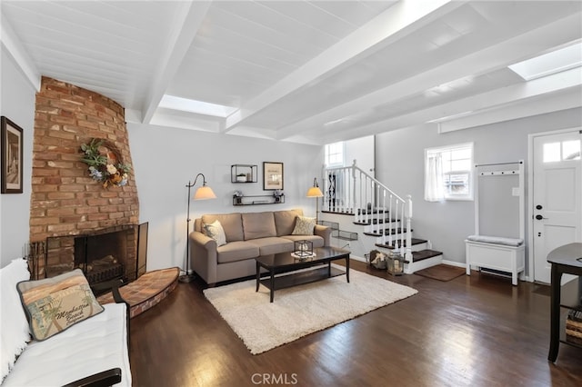 living area featuring a wealth of natural light, a fireplace, beamed ceiling, and stairs