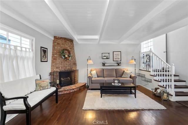 living room with stairs, beam ceiling, a fireplace, and wood finished floors