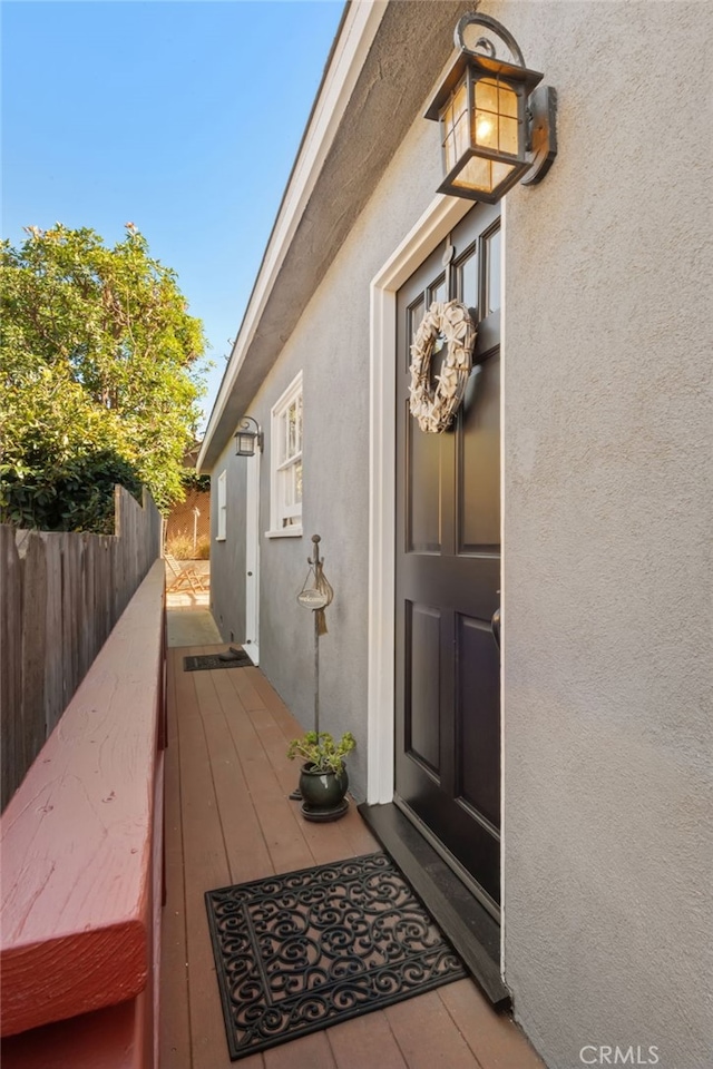 view of exterior entry featuring fence and stucco siding