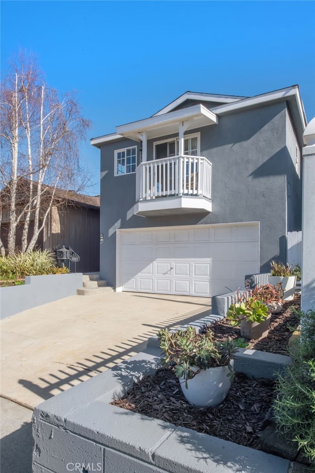 view of front of house featuring a garage, a balcony, driveway, and stucco siding