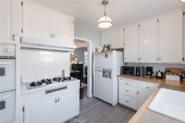 kitchen with decorative backsplash, light wood-style floors, white cabinetry, white appliances, and under cabinet range hood