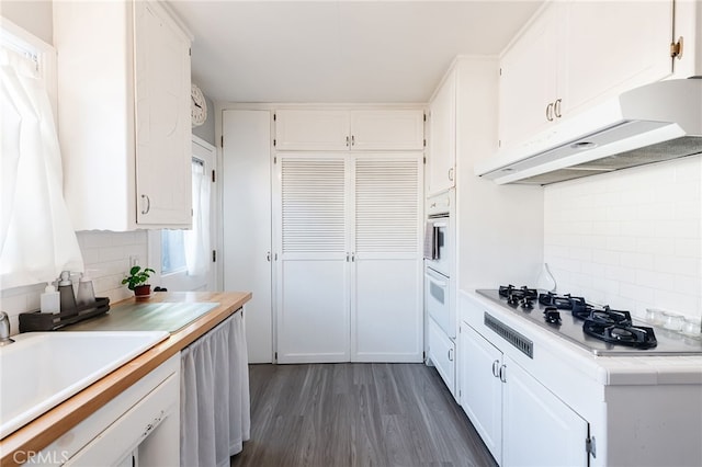 kitchen featuring stainless steel gas stovetop, dark wood-type flooring, white cabinetry, a sink, and under cabinet range hood