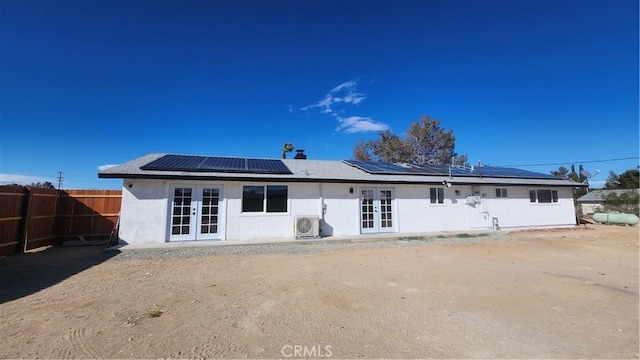 420 N Yorktown St, Ridgecrest, CA 93555 - back of house featuring fence, french doors, ac unit, roof mounted solar panels, and stucco siding