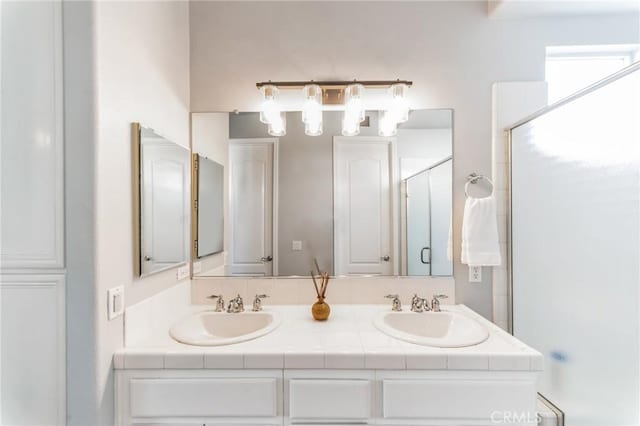 bathroom featuring double vanity, an enclosed shower, and a sink