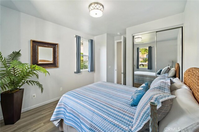 bedroom featuring a closet, baseboards, and wood finished floors