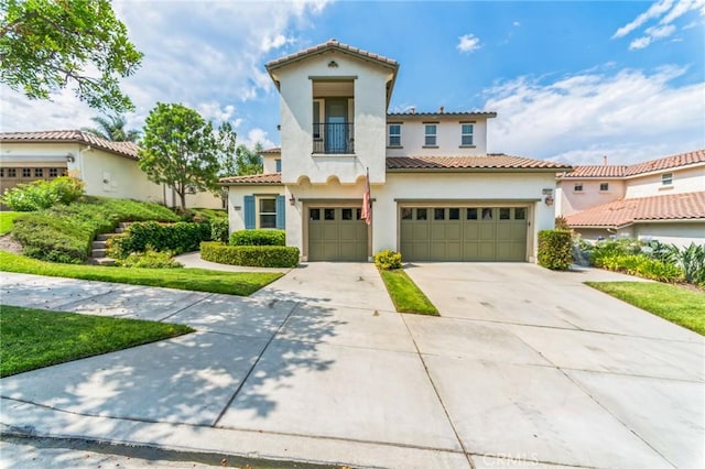 mediterranean / spanish house with a tile roof, driveway, a balcony, and stucco siding