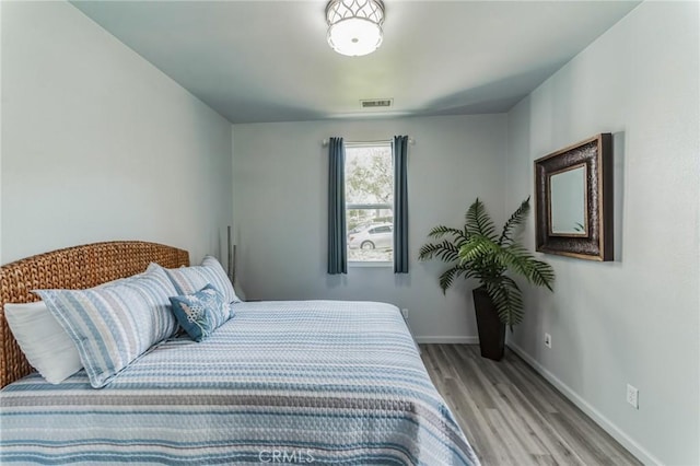 bedroom featuring light wood-type flooring, visible vents, and baseboards