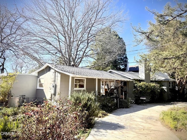 view of front of property featuring driveway, a shingled roof, and stucco siding