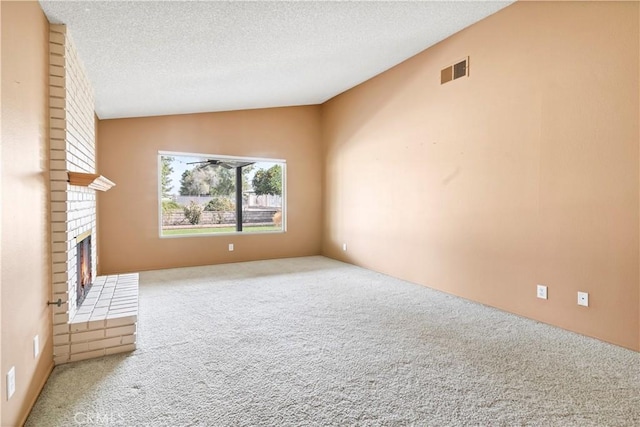 unfurnished living room with carpet floors, lofted ceiling, visible vents, a brick fireplace, and a textured ceiling