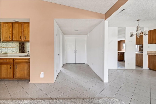 kitchen featuring brown cabinets, light tile patterned floors, tasteful backsplash, light countertops, and an inviting chandelier