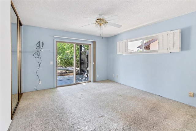 carpeted empty room with ceiling fan and a textured ceiling