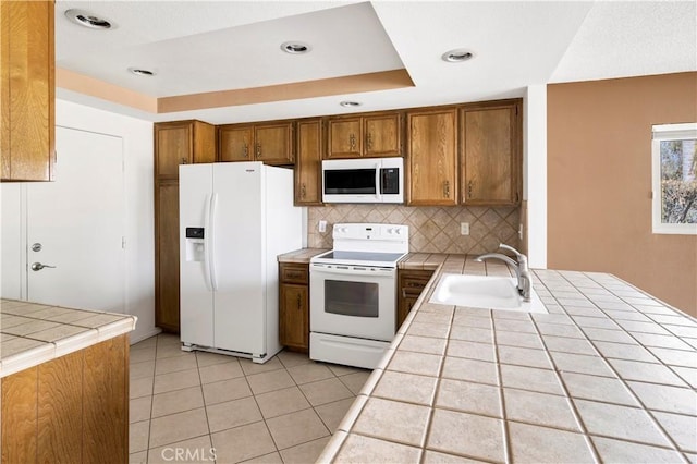 kitchen featuring tile countertops, white appliances, a sink, and brown cabinets