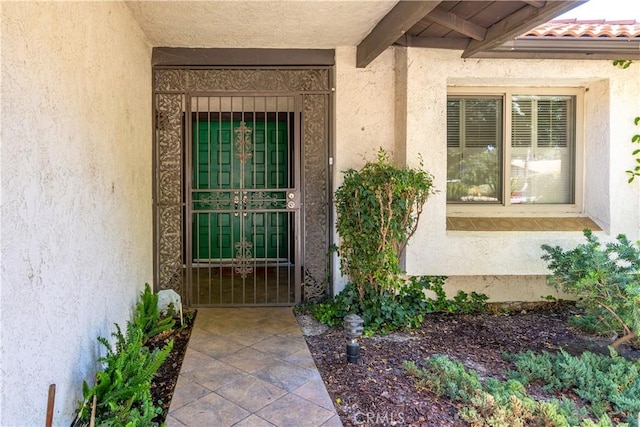 view of exterior entry featuring a tiled roof and stucco siding