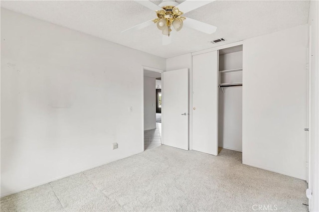 unfurnished bedroom with ceiling fan, visible vents, a closet, and light colored carpet