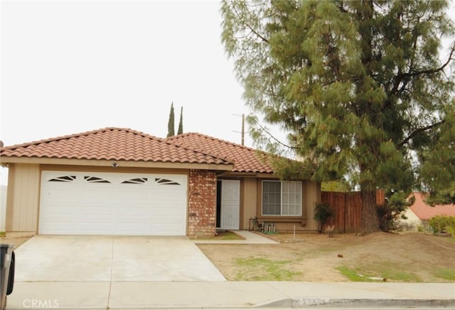 view of front of property featuring brick siding, fence, a garage, driveway, and a tiled roof