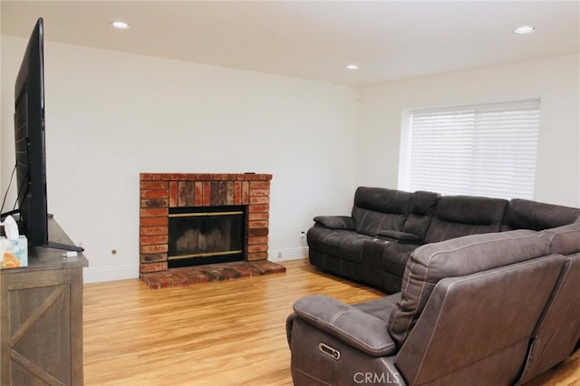 living room featuring light wood finished floors, a brick fireplace, baseboards, and recessed lighting