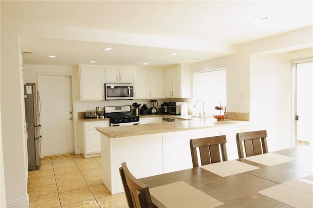 kitchen with stainless steel appliances, light countertops, white cabinetry, and a peninsula