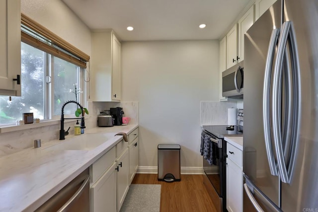 kitchen with dark wood-type flooring, white cabinetry, stainless steel appliances, and a sink