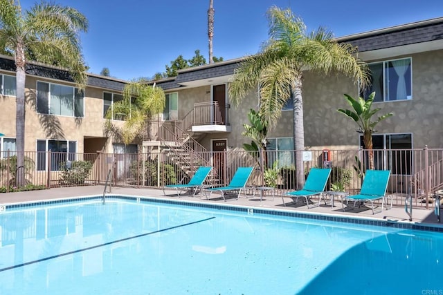 community pool with a patio and fence