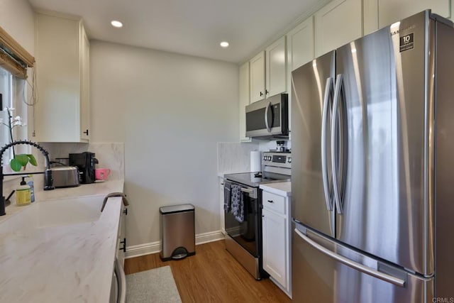 kitchen with appliances with stainless steel finishes, recessed lighting, wood finished floors, and white cabinets