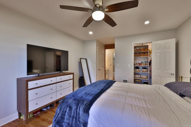 bedroom featuring visible vents, a ceiling fan, wood finished floors, a walk in closet, and recessed lighting