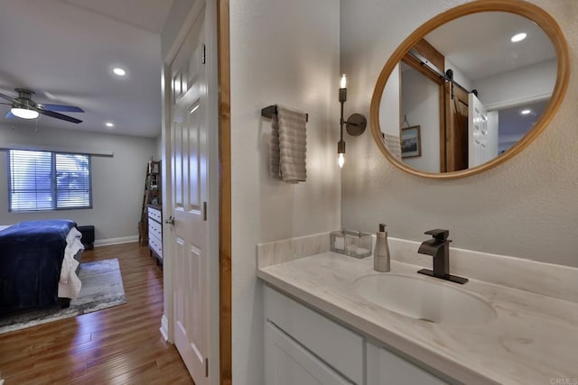 bathroom featuring ceiling fan, recessed lighting, wood finished floors, vanity, and baseboards