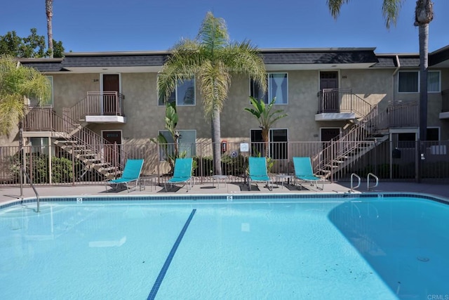 pool featuring stairs, a patio area, and fence