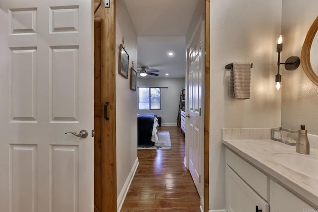 corridor with a sink, wood finished floors, and baseboards