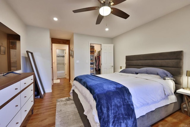 bedroom with a spacious closet, wood finished floors, a ceiling fan, and recessed lighting