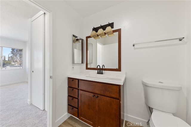 half bathroom featuring toilet, vanity, and baseboards