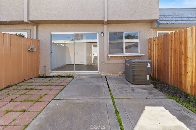 doorway to property featuring a patio, fence, cooling unit, and stucco siding