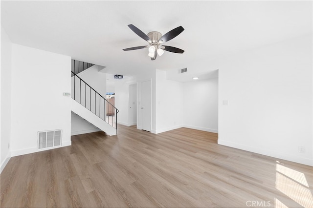 unfurnished living room with light wood-style floors, stairs, and visible vents