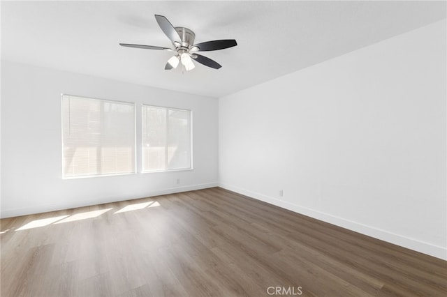 empty room featuring a ceiling fan, baseboards, and wood finished floors