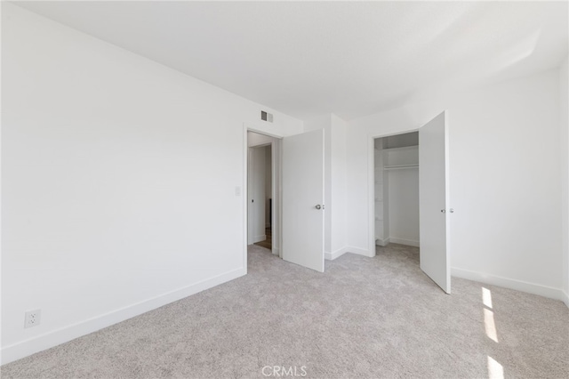 unfurnished bedroom featuring light colored carpet, a closet, visible vents, and baseboards