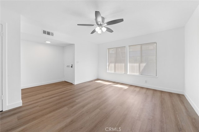 spare room featuring ceiling fan, wood finished floors, visible vents, and baseboards