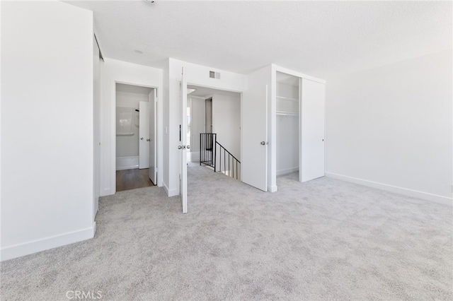 unfurnished bedroom with baseboards, visible vents, a textured ceiling, carpet floors, and a closet