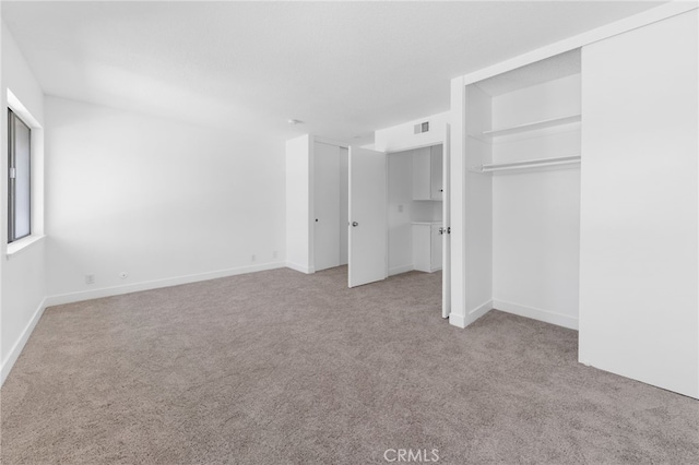 unfurnished bedroom featuring two closets, carpet flooring, visible vents, and baseboards