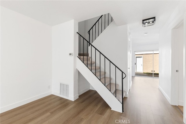 staircase featuring visible vents, baseboards, and wood finished floors