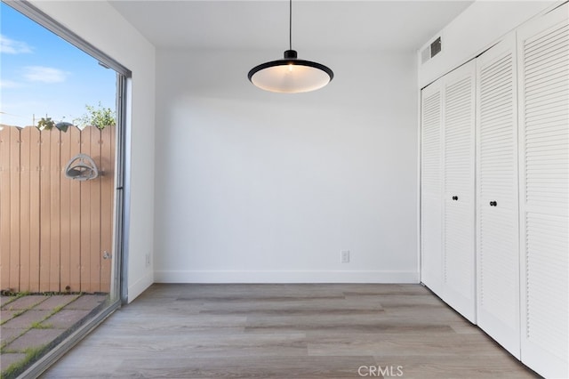 unfurnished dining area with light wood-style flooring, visible vents, and baseboards