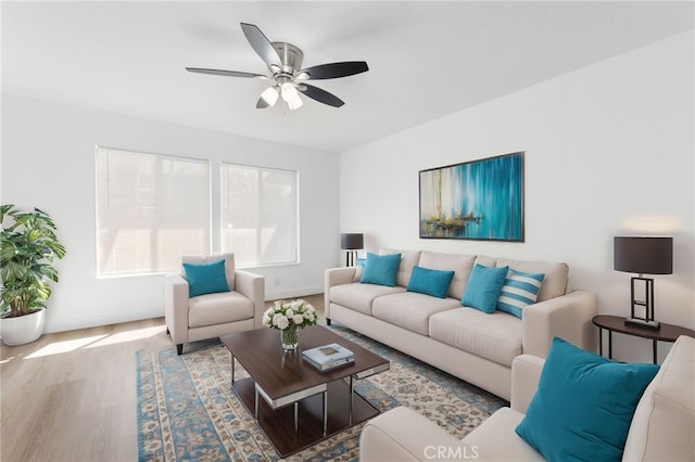 living room featuring a ceiling fan, baseboards, and wood finished floors