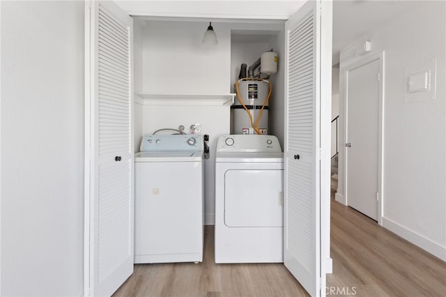 washroom with laundry area, baseboards, light wood-style floors, washing machine and dryer, and gas water heater