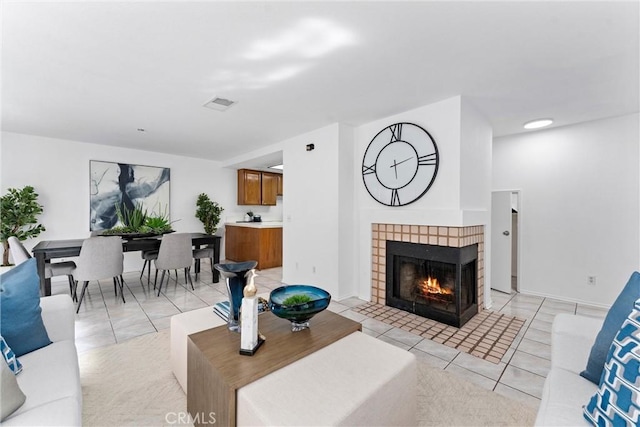 living area with baseboards, visible vents, a tiled fireplace, and light tile patterned flooring