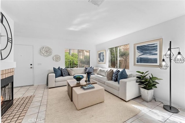 living area with a brick fireplace, light tile patterned flooring, and baseboards