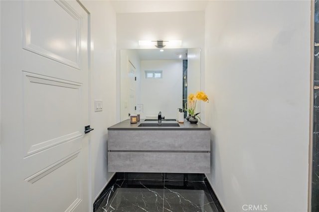 bathroom with marble finish floor, vanity, and baseboards
