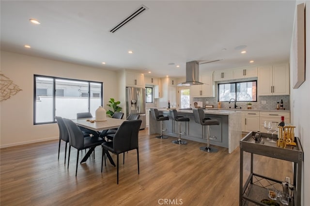 dining room with baseboards, wood finished floors, visible vents, and recessed lighting