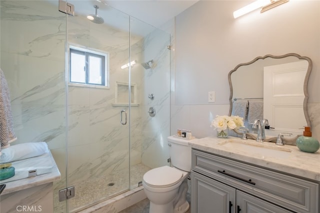 full bath with vanity, a marble finish shower, and toilet
