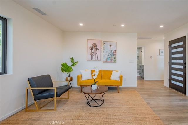 living area with recessed lighting, visible vents, baseboards, and wood finished floors